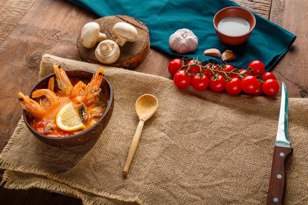 Zuppa di Tom yam con gamberi e latte di cocco sul tavolo su un tovagliolo accanto agli ingredienti. copia spazio. Foto orizzontale