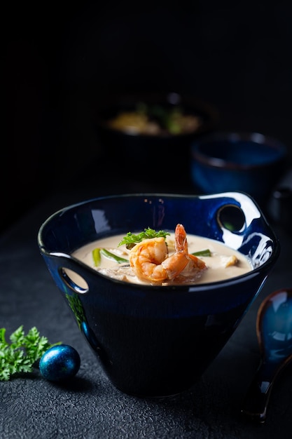 Zuppa di Tom Yum Kung una zuppa di gamberi piccante tradizionale tailandese in una ciotola su sfondo scuro