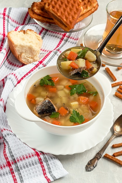 Zuppa di tonno in scatola appena fatta con cracker su calcestruzzo con mestolo