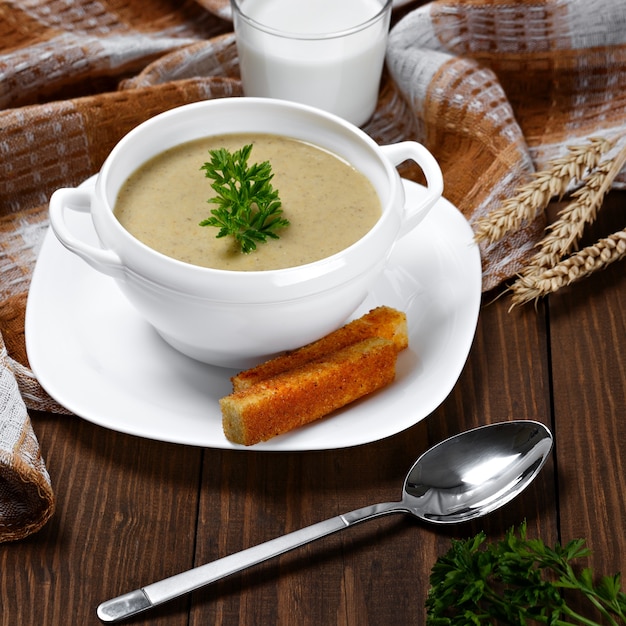 Zuppa di verdure con prezzemolo e pane fritto su un tavolo di legno.