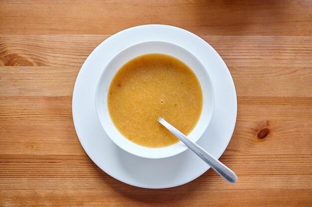 Zuppa di verdure in una ciotola bianca con un cucchiaio in piedi su un tavolo di legno marrone