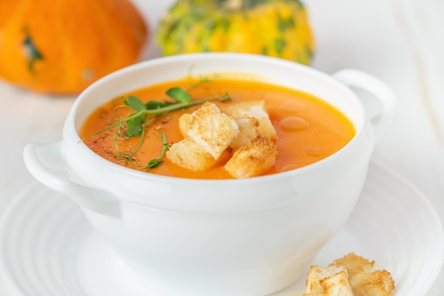 Zuppa di zucca con crostini di pane su sfondo bianco Primo piano