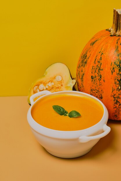 Zuppa di zucca decorata con basilico su fondo arancio