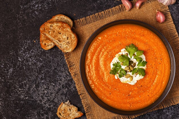 Zuppa di zucca e carote con panna acida, semi e prezzemolo