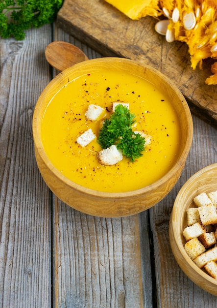 Zuppa di zucca e carote, tadka con panna e prezzemolo sul tavolo di legno scuro. Vista dall'alto.