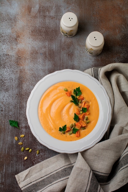 Zuppa di zucca fatta in casa in un piatto di ceramica bianca su un vecchio cemento o pietra