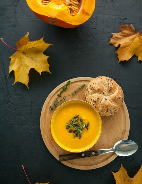 Zuppa di zucca fatta in casa vegana vista dall'alto con semi, erbe e panino