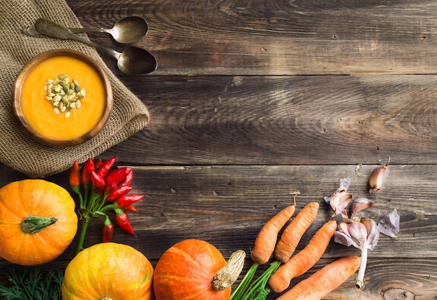 Zuppa di zucca fresca fatta in casa con ingredienti su fondo rustico in legno. Vista dall'alto. Copiare l'area dello spazio.