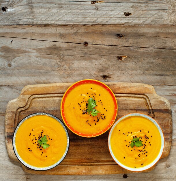 Zuppa di zucca fresca in tre ciotole su un tavolo di legno