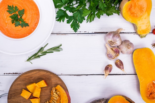 Zuppa di zucca in un piatto bianco e ingredienti