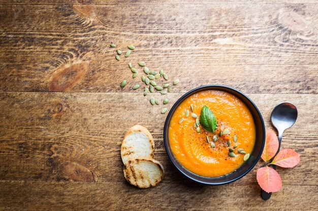 Zuppa di zucca in una banda nera su un di legno. Decorazioni autunnali.