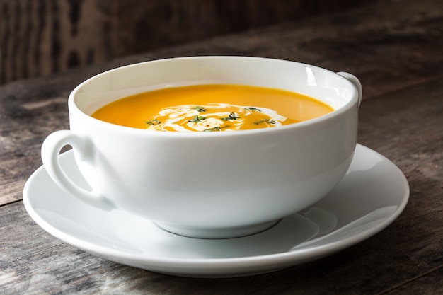 Zuppa di zucca in una ciotola bianca sul tavolo di legno