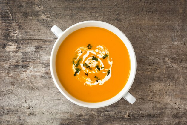 Zuppa di zucca in una ciotola bianca sul tavolo di legno