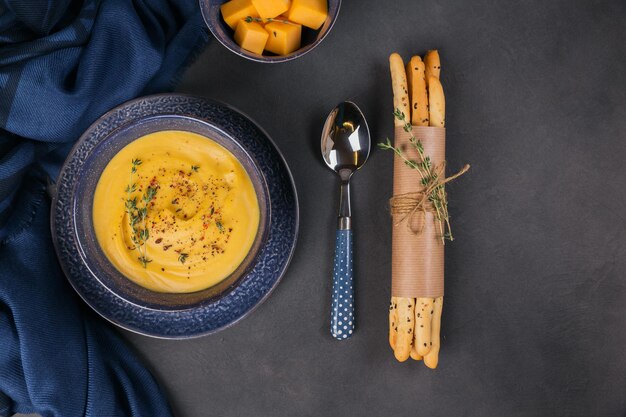 Zuppa di zucca in una ciotola blu condita con erbe fresche