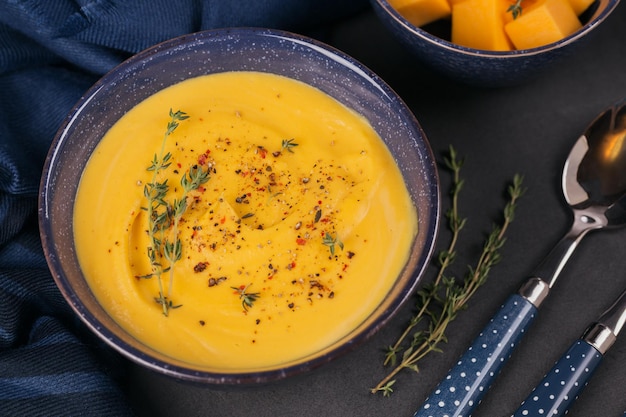 Zuppa di zucca in una ciotola blu condita con erbe fresche