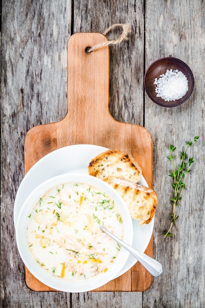 Zuppa fatta in casa con salmone e panna su fondo di legno con crostini di pane