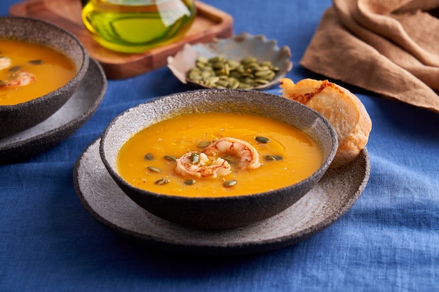 Zuppa pascetariana di crema di zucca e carote con erbette di gamberi e ciabatta tostata in terrina