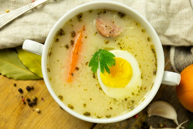 Zuppa polacca tradizionale su un tavolo di legno, con uova e salsiccia, vista dall'alto