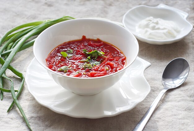 Zuppa rossa di barbabietola vegetariana tradizionale ucraina - borscht con panna acida sul tavolo. Vista dall'alto.