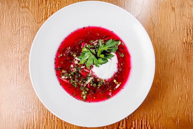 Zuppa rossa in un piatto bianco. Borsch con antipasto di pane.