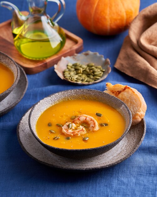 Zuppa rustica pascetariana di crema di zucca e carote con spezie di gamberi e pane tostato in ciotola