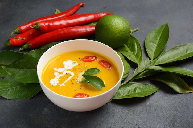 Zuppa thailandese di zucca piccante e latte di cocco con foglie di lime kaffir, peperoncino rosso e polvere di radici di galanga.