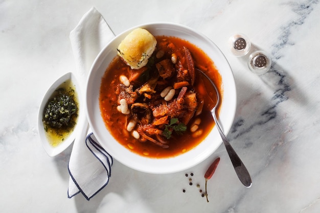 Zuppa ucraina borsch con funghi e fagioli bianchi e ciambelle pampushki su un tavolo di marmo