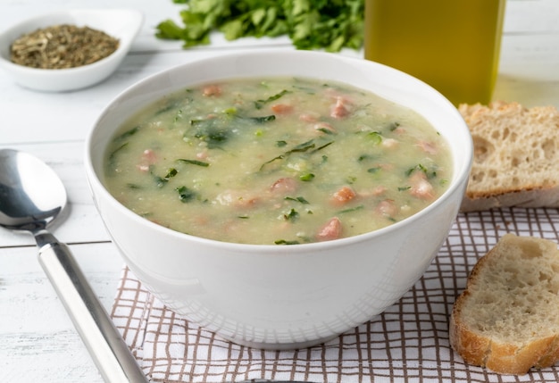 Zuppa verde portoghese tradizionale con cavolo cappuccio e salsiccia di patate in una ciotola con pane