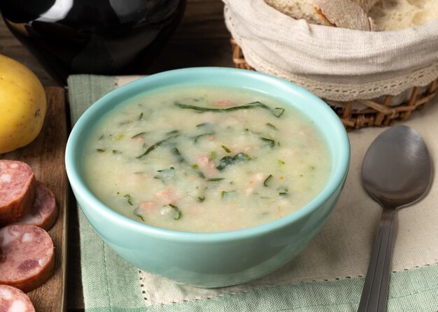 Zuppa verde tradizionale portoghese con cavolo cappuccio e salsiccia in una ciotola con pane e vino