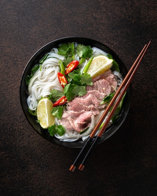 Zuppa vietnamita pho bo con manzo e noodles su uno sfondo scuro vista dall'alto