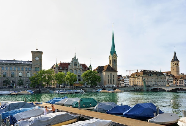 Zurigo, Svizzera - 2 settembre 2016: Chiesa di San Pietro e Chiesa di Fraumunster e barche al molo del fiume Limmat nel centro della città di Zurigo, Svizzera. Persone sullo sfondo