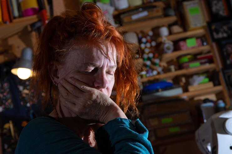 Fotografie a depressed woman sits in a room she supports her head in her hands and has her eyes closed