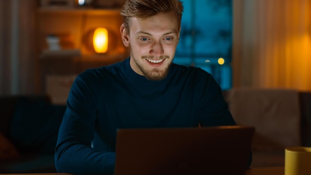 A man sits at a table in front of a laptop.