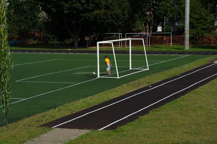Fotografie a schoolboy a football player hits the ball are standing in the goal stadium