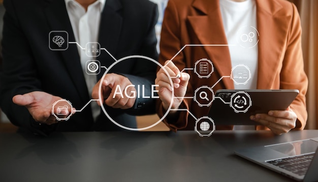 Agile development methodology concept Business hand using laptop computer and tablet with virtual screen Agile icon on modern office