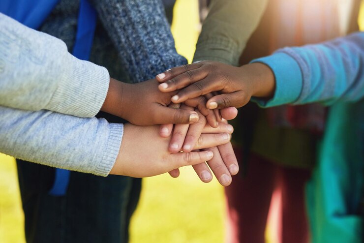 Fotografie all for one and one for all shot of a group of unrecognizable elementary school kids joining their hands together in a huddle outside