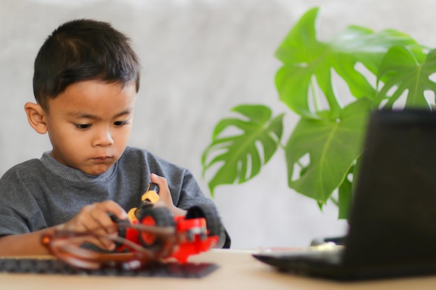 Asian boy students learn at home in coding robot cars and electronic board cables in STEM STEAM mathematics engineering science technology computer code in robotics for kids concept