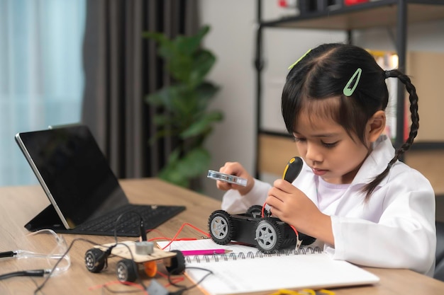 Asian littlle girl constructing and coding robot at STEM classFixing and repair mechanic toy car