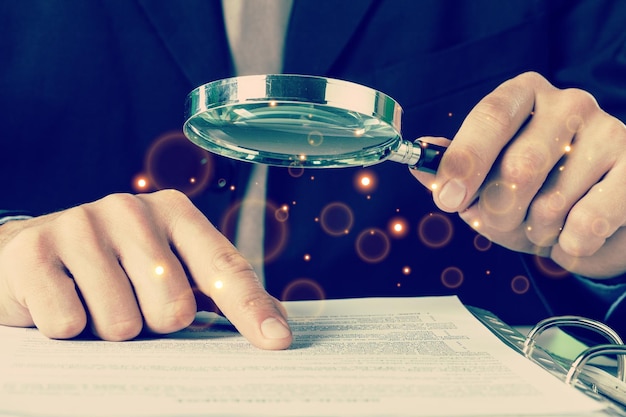Business analytics and statistics. Businessman with report using a magnifying glass.