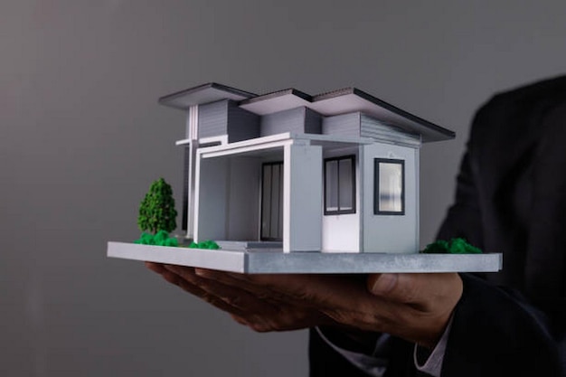 Businessman Hand holding home model mortgage loan concept