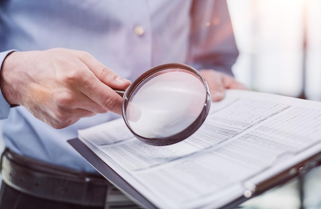 Businessman looking through a magnifying glass to documents