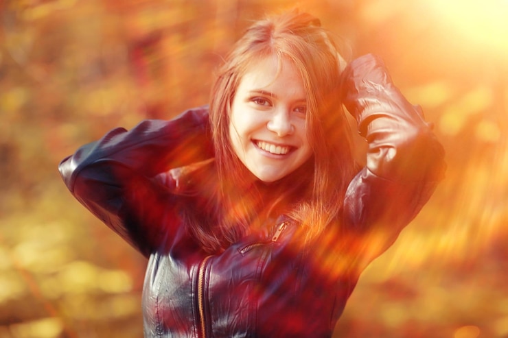 Fotografie cheerful happy young adult girl in sunlight rays and wind hair