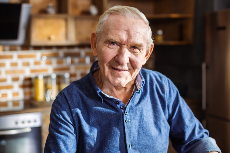 Fotografie close up of a joyful elderly man smiling while standing in the kitchen