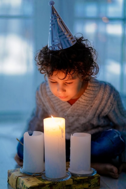 Close-up of boy looking at illuminated burning candle