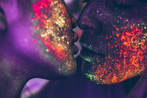 close-up of couple with multi colored face paint kissing
