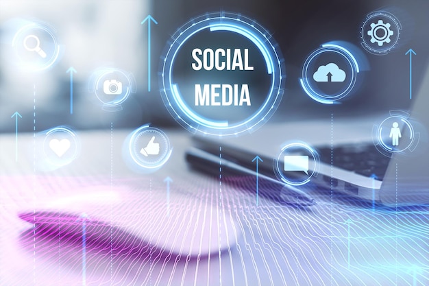 Close up of desk with laptop supplies and glowing social media hologram on blurry background Likes shares and network concept Toned image Double exposure