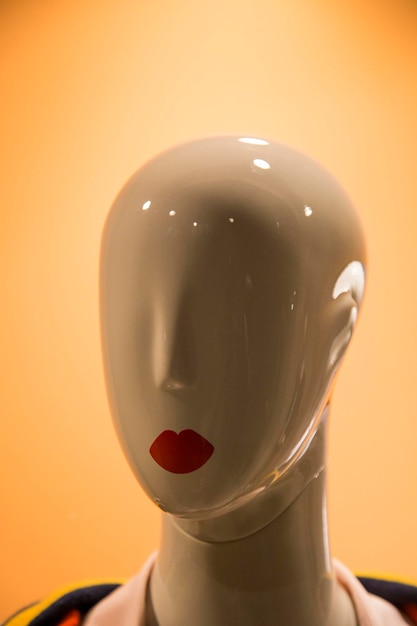 close-up of female mannequin with red lipstick against colored background