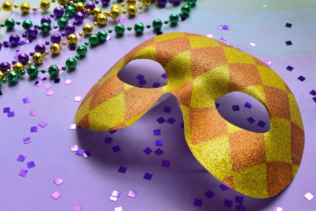 close-up of mask with glitter and rosary beads over purple background