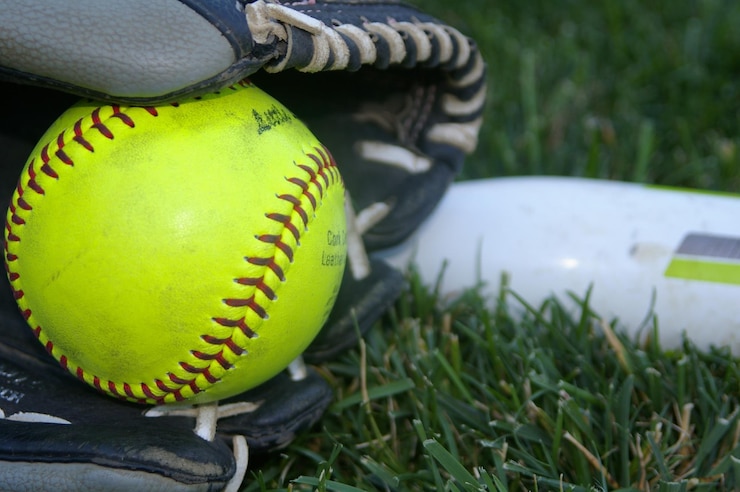 Fotografie close-up of softball on grass in a glove with a bat