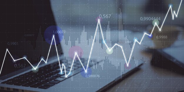 Close up of workplace with laptop and abstract glowing business chart on blurry grid background Digital economy and big data concept Double exposure
